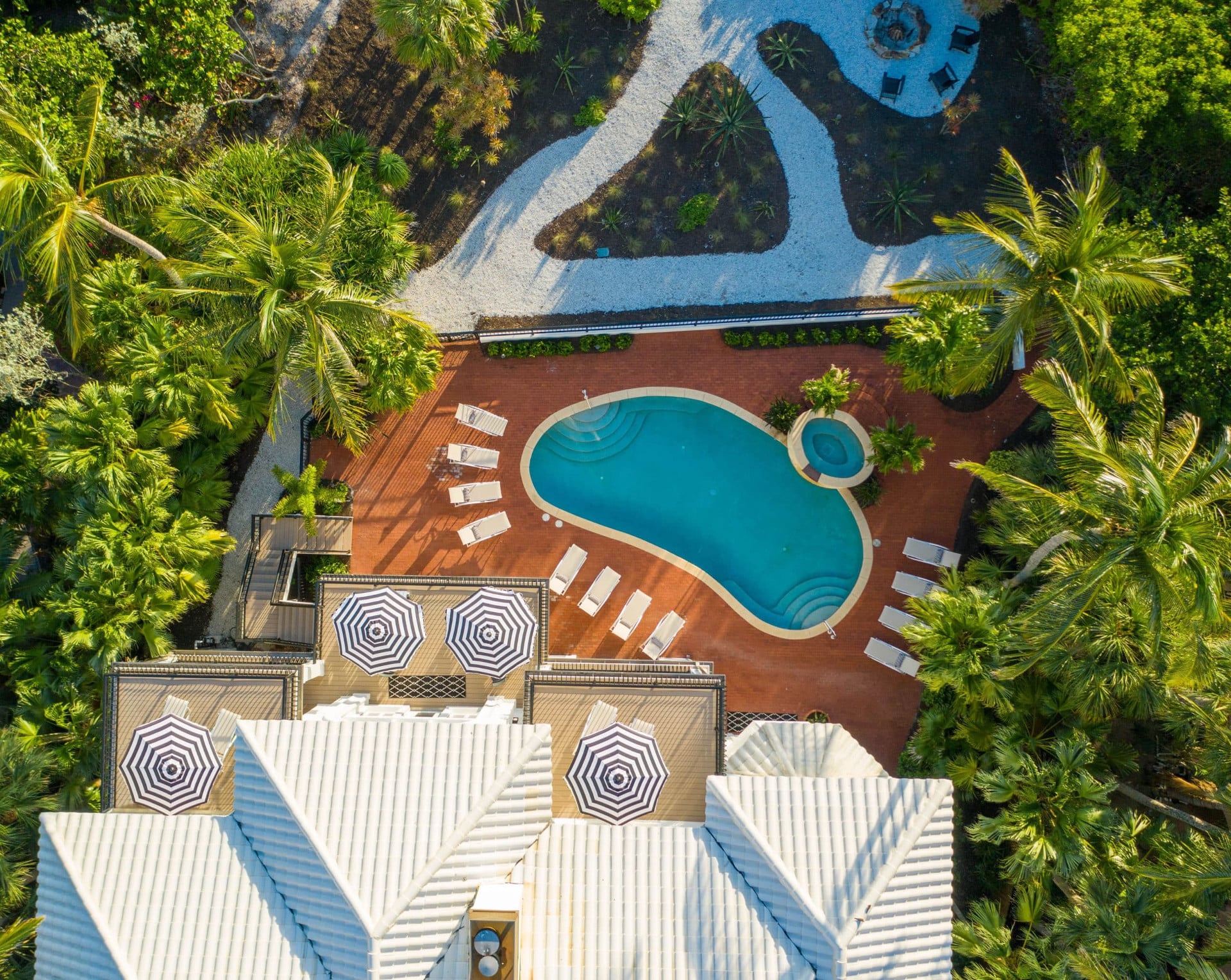 Bird's eye view of the pool area with white chairs, blue striped umbrella's and palm trees at the Sea Palms Estate in Captiva Island, FL