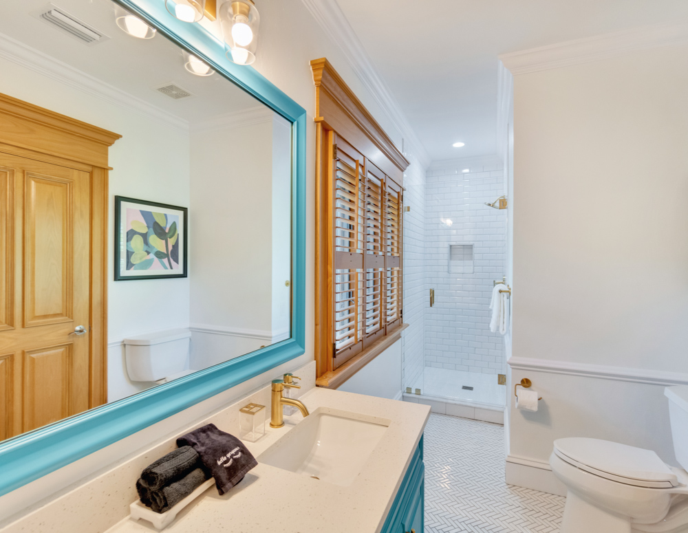 Bathroom with white fixtures and blue trim with standing shower at the Sea Palms Estate in Captiva Island, FL