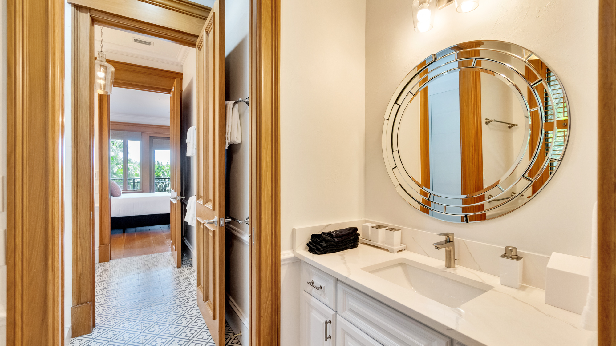 Bathroom with white fixtures and large circle mirror adjacent to bedroom at the Sea Palms Estate in Captiva Island, FL