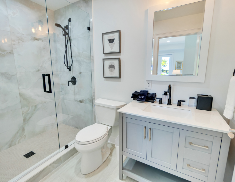 Bathroom with standing shower and white fixtures in front of mirror at the Sea Palms Estate in Captiva Island, FL