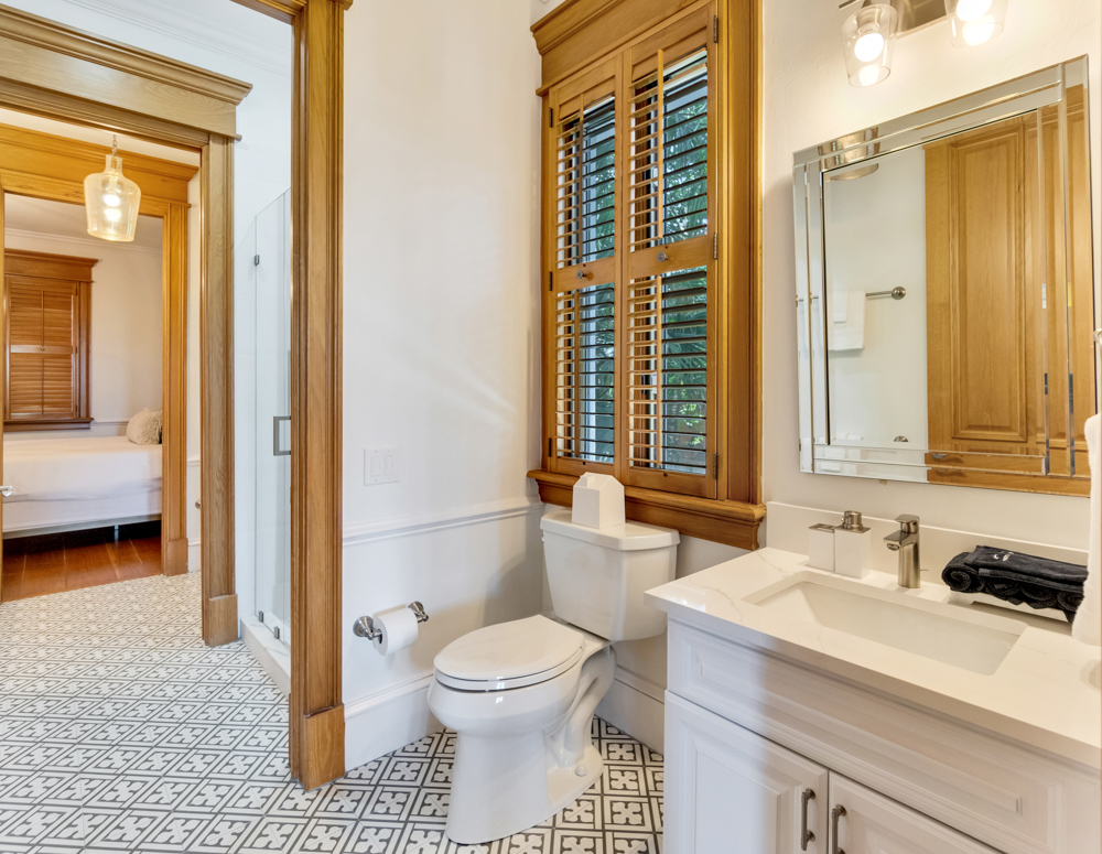Bathroom with white fixtures and wooden trim adjacent to bedroom at the Sea Palms Estate in Captiva Island, FL